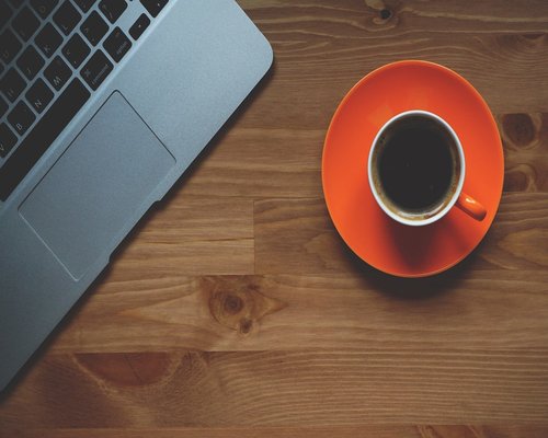 A person taking a short break from computer work, looking away with a cup of coffee